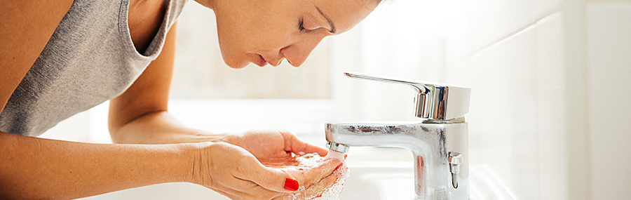 Young woman washing her face in the morning, looking into camera and smiling. Image taken with Nikon D800 and 24-70mm pro lens, developed and processed from RAW and distributed in XXXL size. Location: Berlin, Germany, Europe