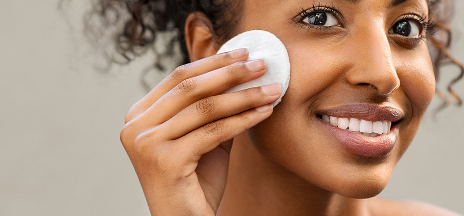 vrouw die haar gecombineerde huid reinigt met een watje